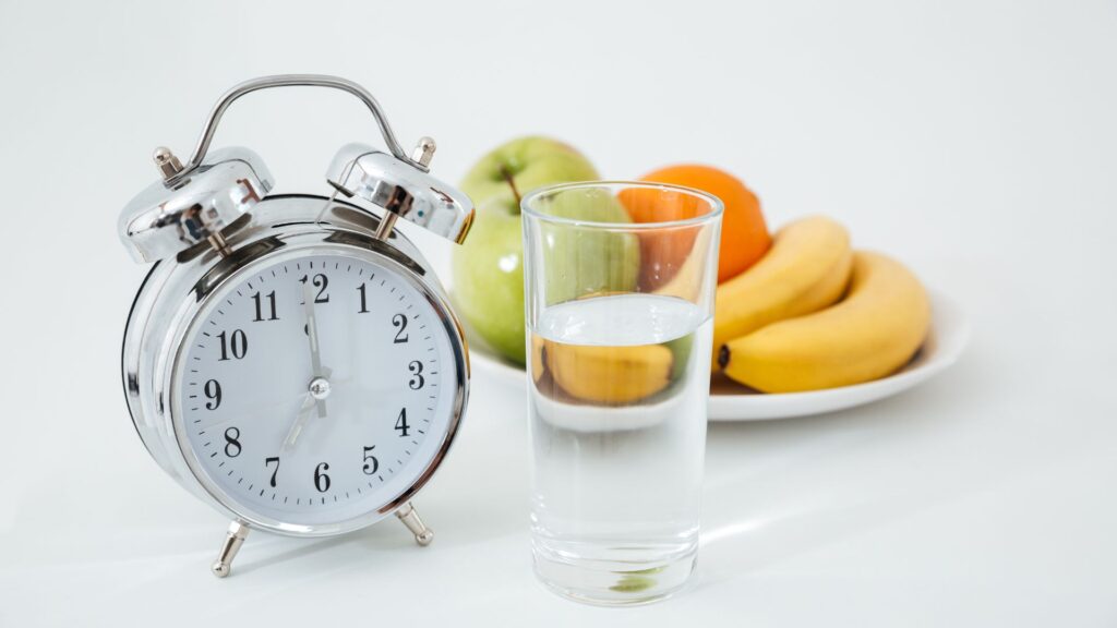 relogio com um copo de agua e frutas