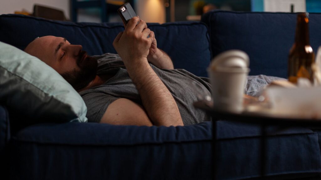 Homem deitado no sofa ao celular