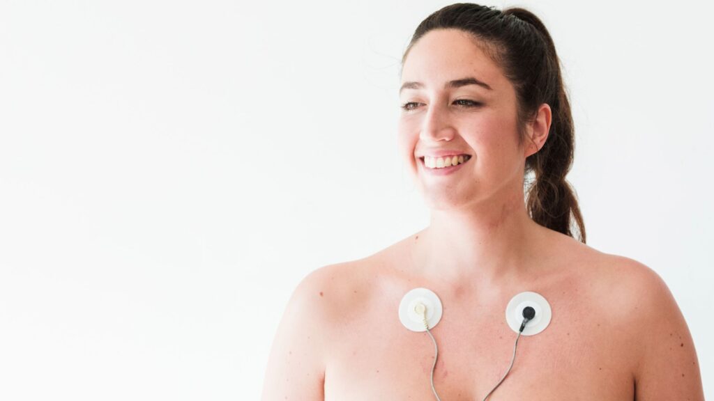 Mulher jovem sorrindo com eletrodos no corpo