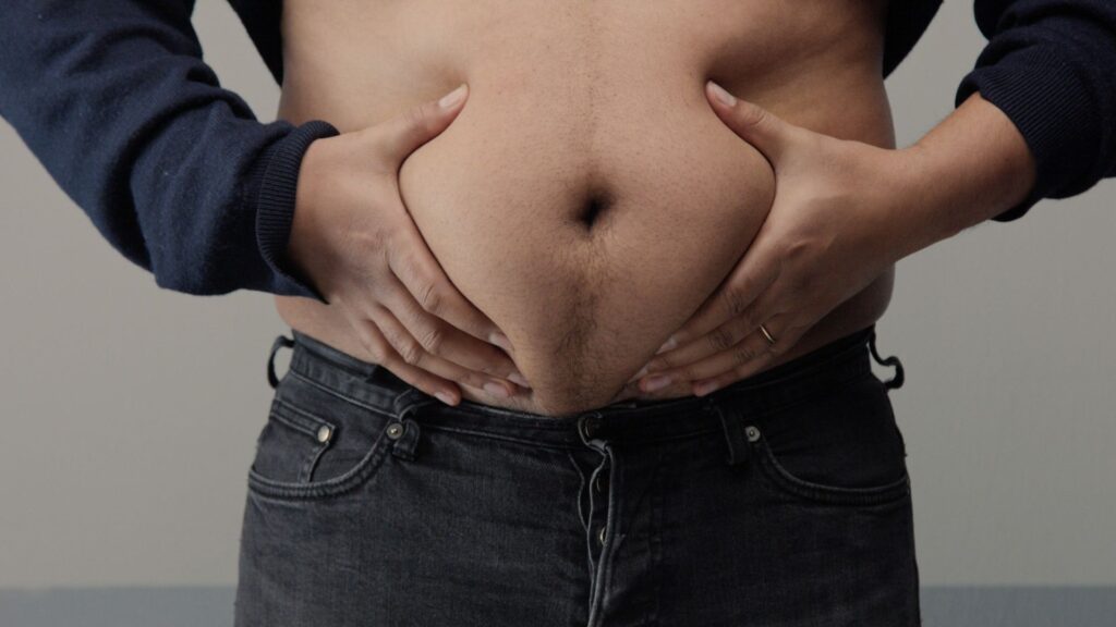 Homem acima do peso segurando gordura abdominal
