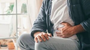 Homem com a mão na região do estômago, representando desconforto abdominal