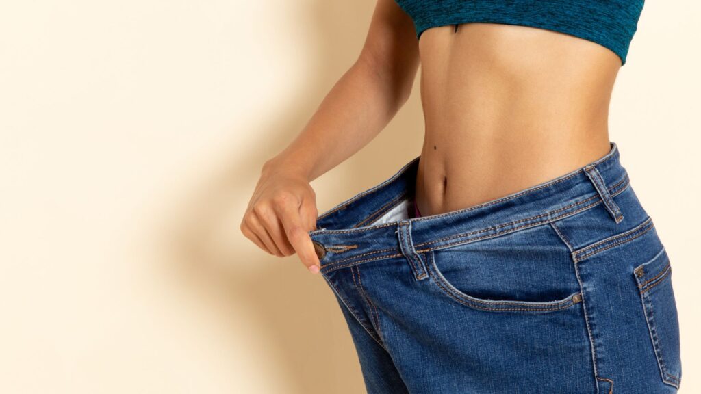 Mulher jovem com corpo fitness usando camisa e jeans.