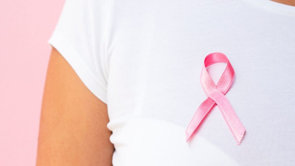 mulher com camiseta branca com fita rosa do cancer de mama